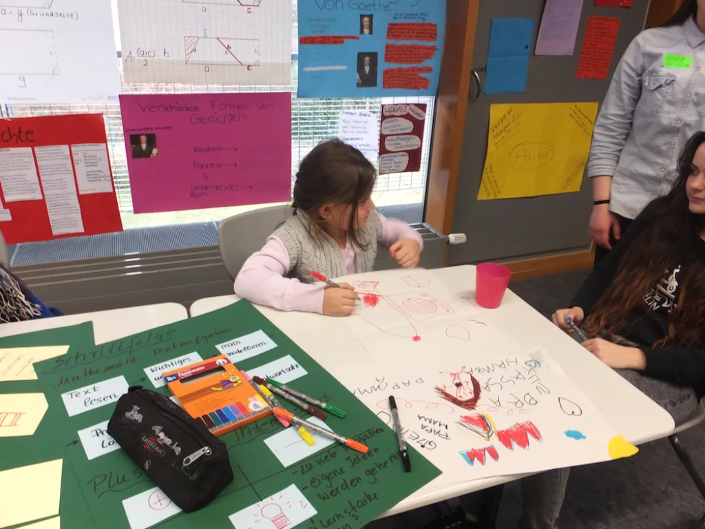 Kinder arbeiten an einem Tisch mit Bastelmaterial.